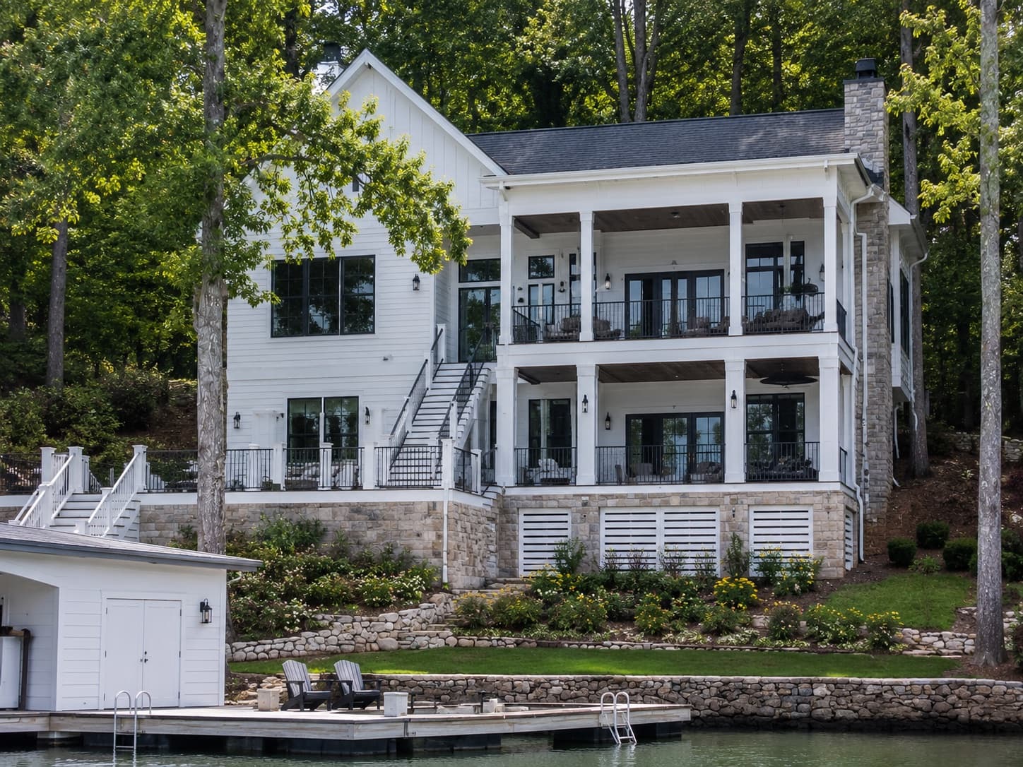 White lake-house exterior with stone foundation and double porches on Lake Keowee in Clemson